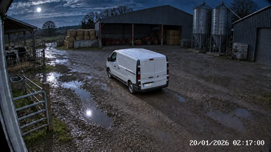 Un utilitaire dans une cour de ferme la nuit, éclairé par la caméra